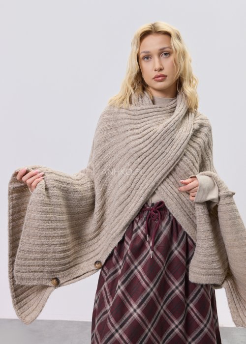 Beżowy damski kardigan o luźnym, oversize’owym kroju z grubego, prążkowanego splotu, noszony nonszalancko na ramionach