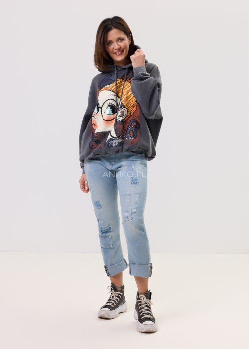 Grafitowa damska bluza z kapturem o luźnym kroju, z dużym artystycznym nadrukiem kobiecej twarzy z okularami i cekinowymi akcentami, noszona z jasnymi jeansami.