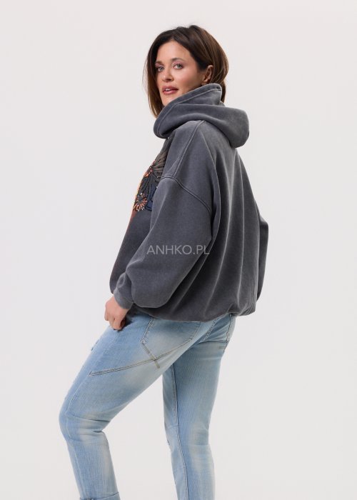Grafitowa damska bluza z kapturem o luźnym kroju, z dużym artystycznym nadrukiem kobiecej twarzy z okularami i cekinowymi akcentami, noszona z jasnymi jeansami.