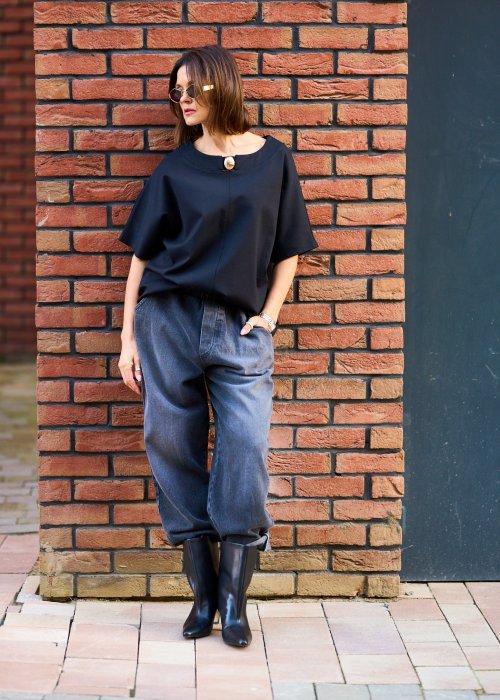 Antracytowe jeansy damskie o luźnym kroju z podwiniętymi nogawkami, stylizowane z czarnym topem i botkami na obcasie w miejskim looku.