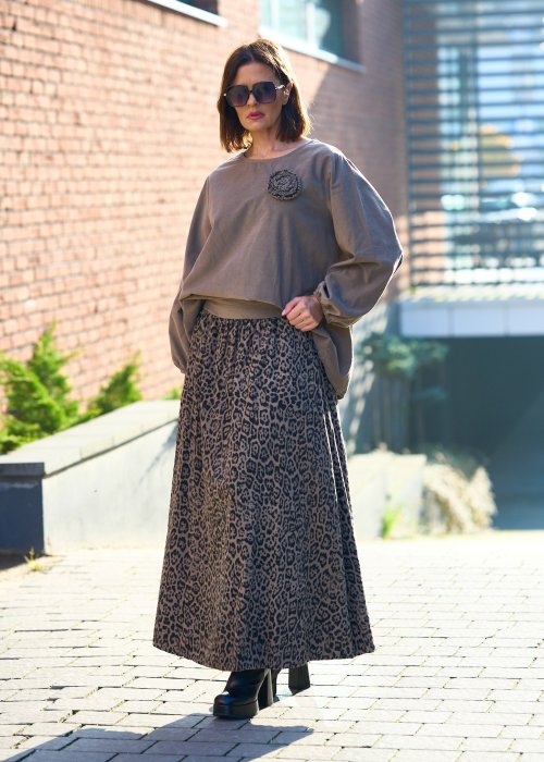 Stylowa kobieta w beżowej bluzce z aplikacją kwiatową i długiej spódnicy w panterkowy wzór