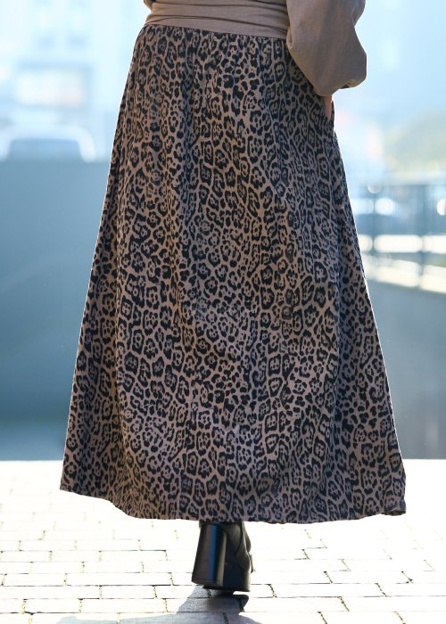 Stylowa kobieta w beżowej bluzce z aplikacją kwiatową i długiej spódnicy w panterkowy wzór