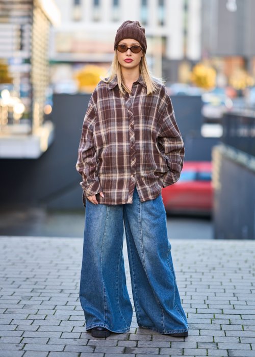 Koszula oversize w brązowo-beżową kratę z długim rękawem i guzikami, stylizacja z jeansami i czapką.