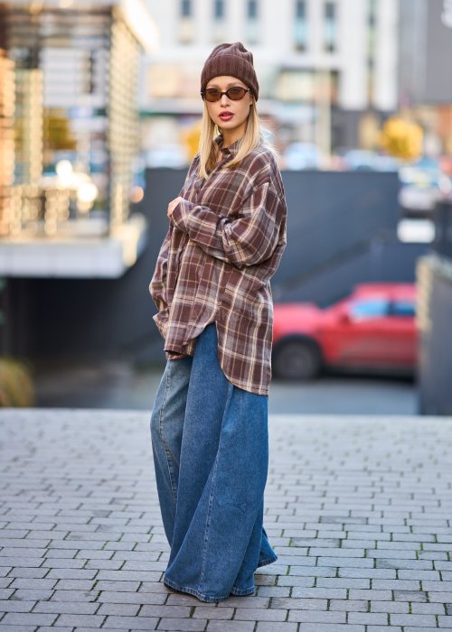 Koszula oversize w brązowo-beżową kratę z długim rękawem i guzikami, stylizacja z jeansami i czapką.