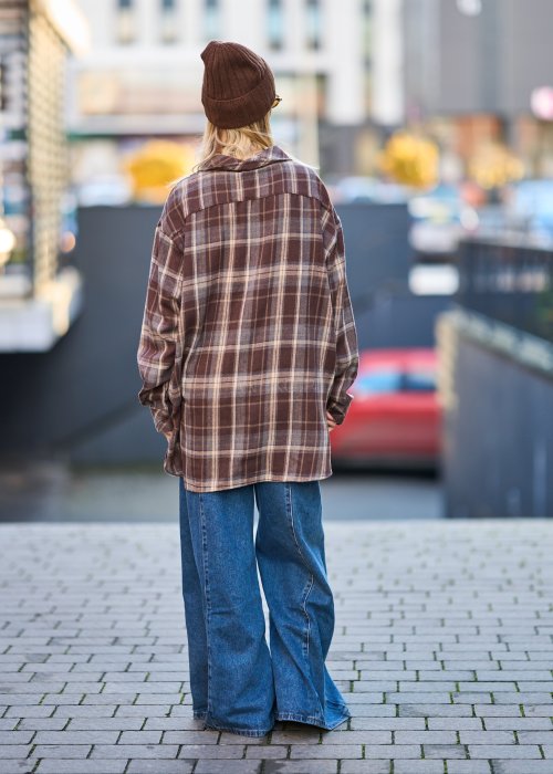 Koszula oversize w brązowo-beżową kratę z długim rękawem i guzikami, stylizacja z jeansami i czapką.