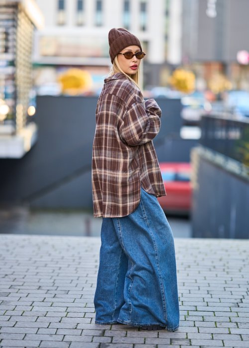 Koszula oversize w brązowo-beżową kratę z długim rękawem i guzikami, stylizacja z jeansami i czapką.