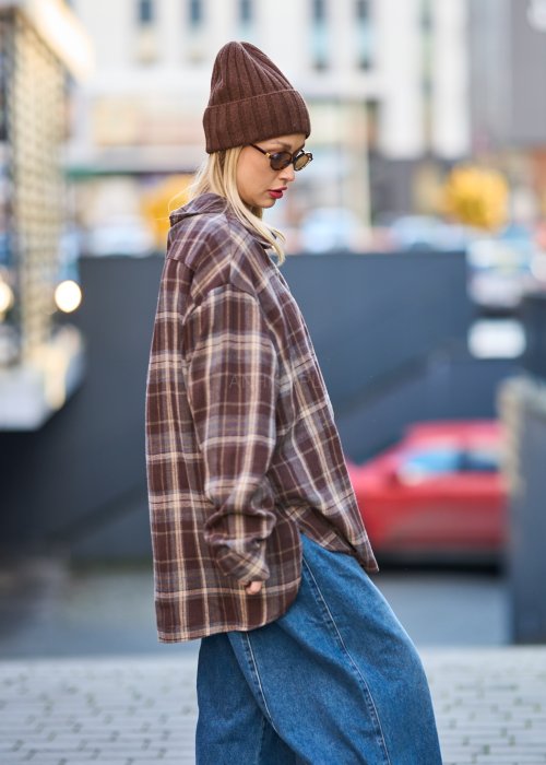 Koszula oversize w brązowo-beżową kratę z długim rękawem i guzikami, stylizacja z jeansami i czapką.