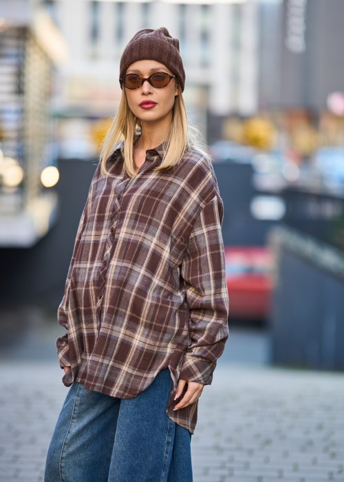 Koszula oversize w brązowo-beżową kratę z długim rękawem i guzikami, stylizacja z jeansami i czapką.