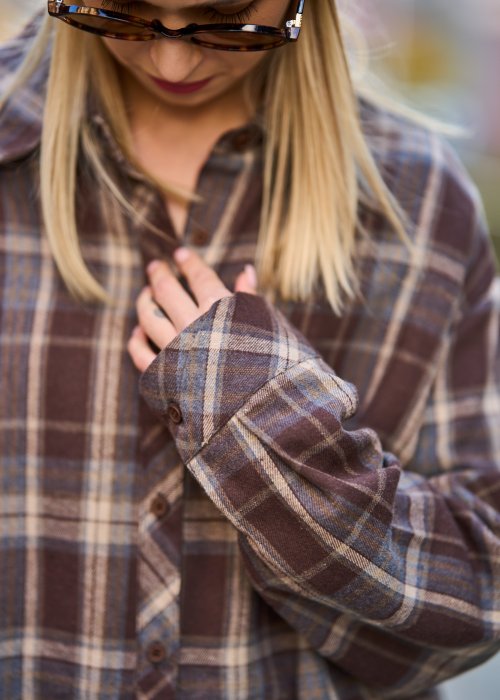 Koszula oversize w brązowo-beżową kratę z długim rękawem i guzikami, stylizacja z jeansami i czapką.