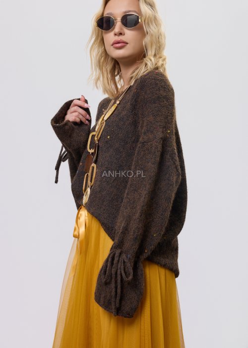 Brązowy sweter damski o luźnym kroju z ozdobnym wiązaniem na rękawach, zestawiony z musztardową spódnicą w stylu casual
