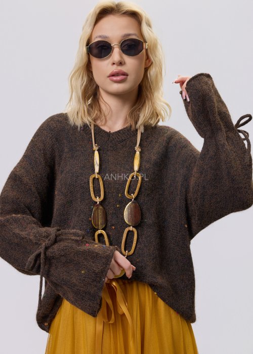 Brązowy sweter damski o luźnym kroju z ozdobnym wiązaniem na rękawach, zestawiony z musztardową spódnicą w stylu casual