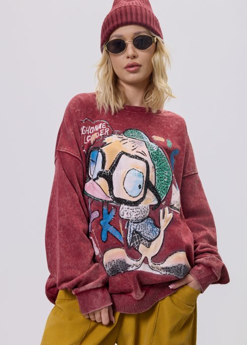 Bordowa bluza damska z efektem sprania i dużym, artystycznym nadrukiem, zestawiona z musztardowymi spodniami w stylu streetwear