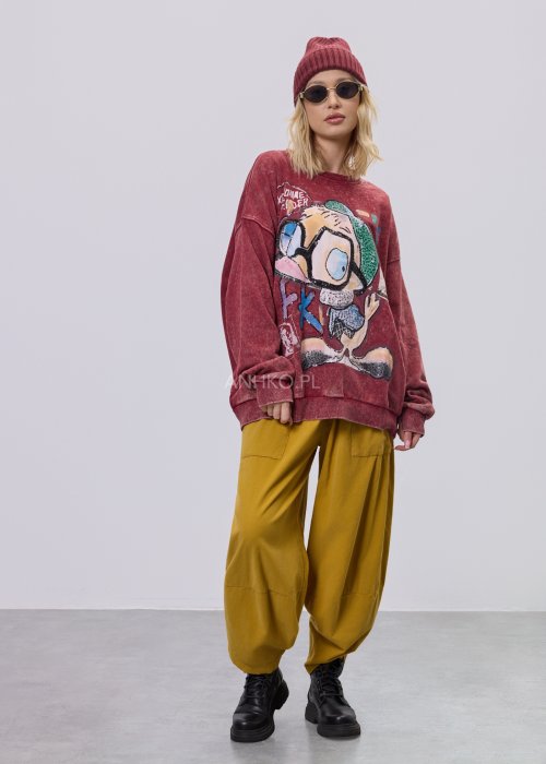 Bordowa bluza damska z efektem sprania i dużym, artystycznym nadrukiem, zestawiona z musztardowymi spodniami w stylu streetwear