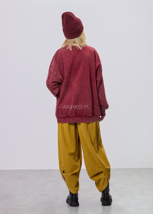 Bordowa bluza damska z efektem sprania i dużym, artystycznym nadrukiem, zestawiona z musztardowymi spodniami w stylu streetwear