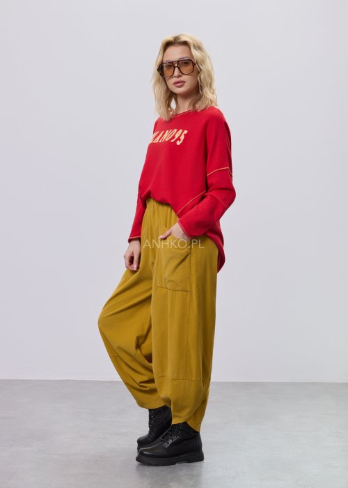 Czerwona bluza damska oversize z haftem „Milano 95” i kontrastowymi przeszyciami, zestawiona z musztardowymi spodniami w stylizacji miejskiej.