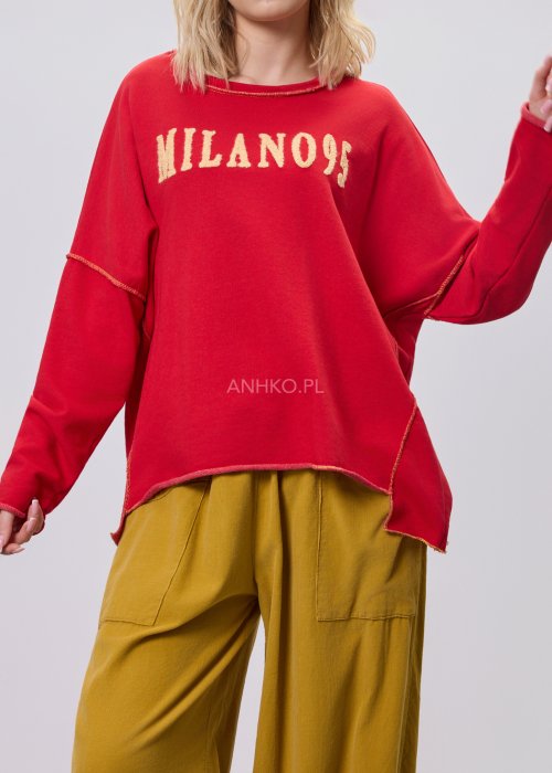 Czerwona bluza damska oversize z haftem „Milano 95” i kontrastowymi przeszyciami, zestawiona z musztardowymi spodniami w stylizacji miejskiej.