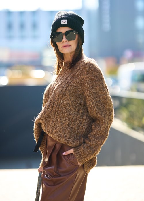 Brązowy sweter damski o grubym splocie z wyrazistym wzorem warkoczowym i luźnym krojem na chłodniejsze dni