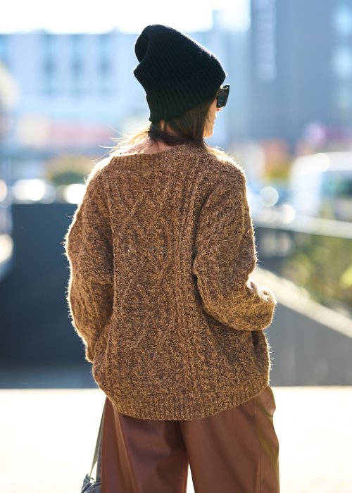 Brązowy sweter damski o grubym splocie z wyrazistym wzorem warkoczowym i luźnym krojem na chłodniejsze dni