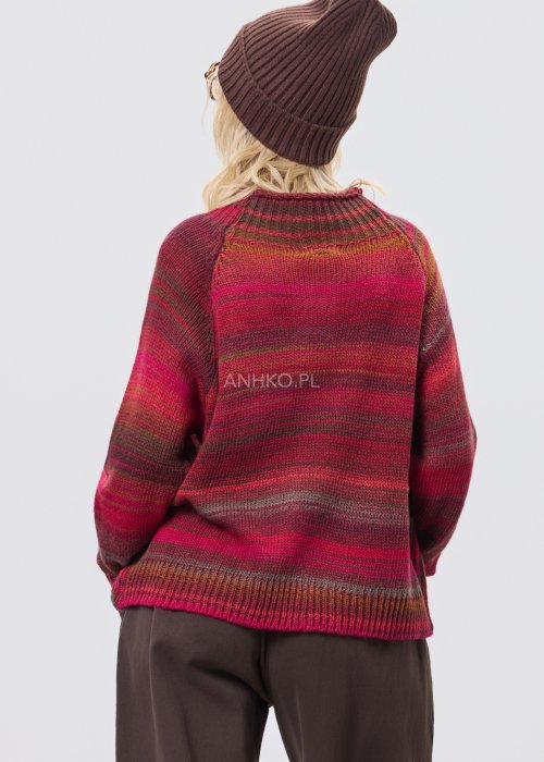 Bordowy sweter damski w wielobarwne paski w odcieniach ziemi, zestawiony z brązowymi spodniami w stylizacji casual na chłodniejsze dni.