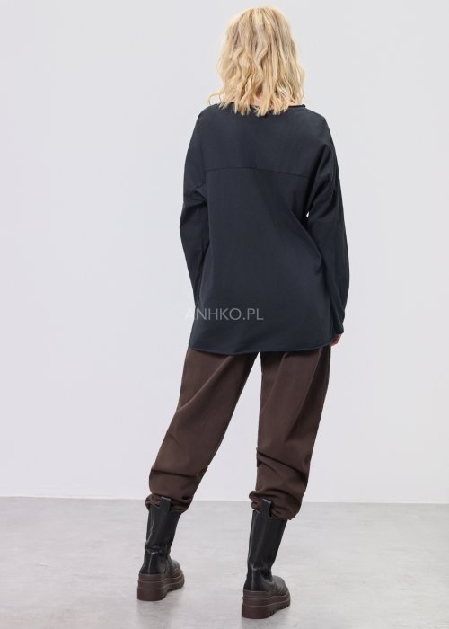 Brązowe spodnie sztruksowe o swobodnym kroju z elastyczną talią i kieszeniami zapinanymi na guziki, zestawione z botkami w stylizacji miejskiej.