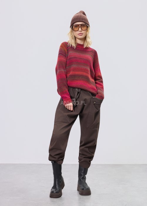 Brązowe spodnie sztruksowe o swobodnym kroju z elastyczną talią i kieszeniami zapinanymi na guziki, zestawione z botkami w stylizacji miejskiej.
