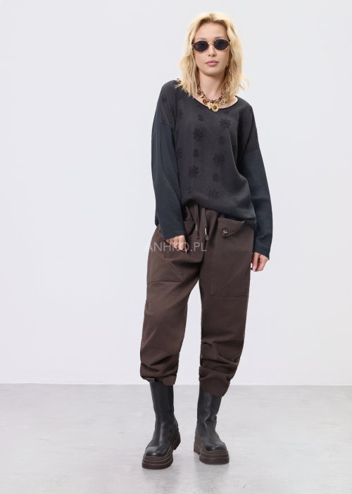 Czarna bluzka damska oversize z subtelnym tłoczonym wzorem, długim rękawem i okrągłym dekoltem, w stylizacji z brązowymi spodniami.