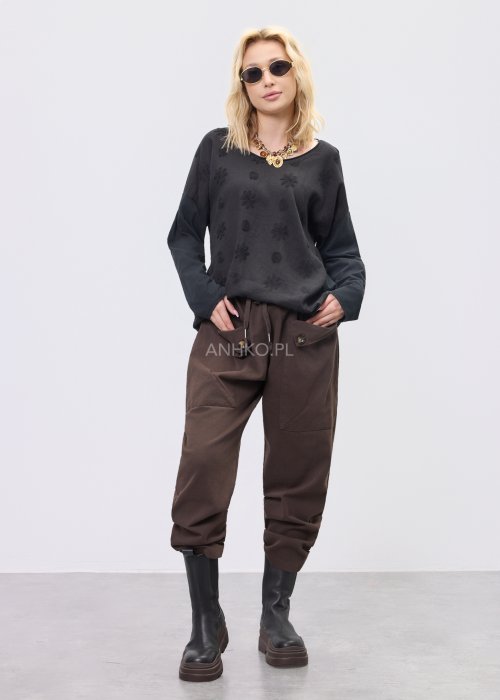 Czarna bluzka damska oversize z subtelnym tłoczonym wzorem, długim rękawem i okrągłym dekoltem, w stylizacji z brązowymi spodniami.