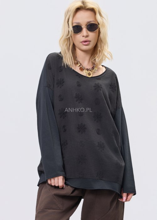 Czarna bluzka damska oversize z subtelnym tłoczonym wzorem, długim rękawem i okrągłym dekoltem, w stylizacji z brązowymi spodniami.