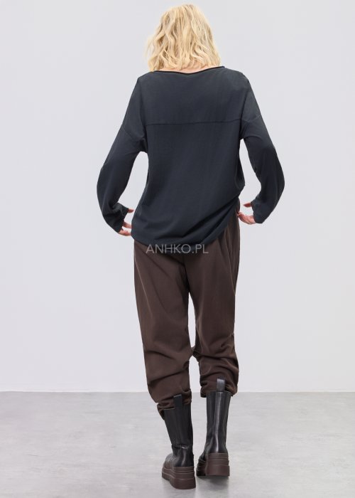 Czarna bluzka damska oversize z subtelnym tłoczonym wzorem, długim rękawem i okrągłym dekoltem, w stylizacji z brązowymi spodniami.