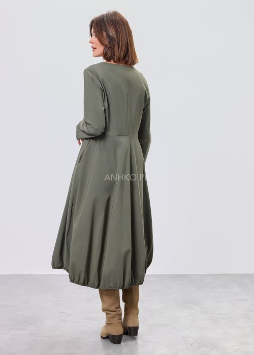 Ciemnozielona sukienka midi z długim rękawem, odcięciem w talii i kieszeniami, stylizowana z beżowymi kozakami.