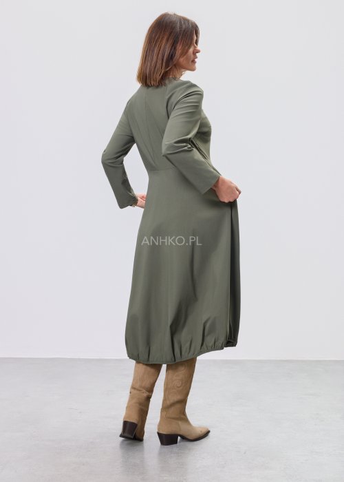Ciemnozielona sukienka midi z długim rękawem, odcięciem w talii i kieszeniami, stylizowana z beżowymi kozakami.