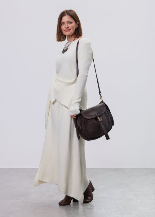 Śmietankowy komplet dzianinowy damski z asymetryczną tuniką i szerokimi spodniami, stylizowany z brązowymi botkami i torebką w minimalistycznym wnętrzu.