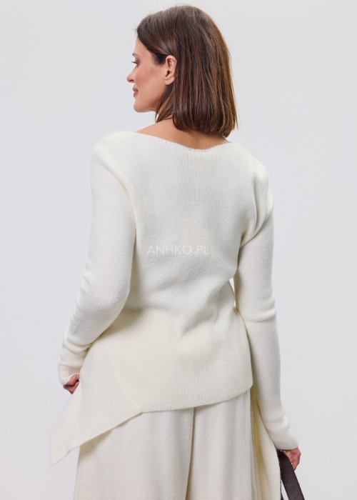 Śmietankowy komplet dzianinowy damski z asymetryczną tuniką i szerokimi spodniami, stylizowany z brązowymi botkami i torebką w minimalistycznym wnętrzu.