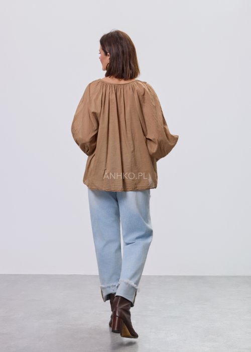 Camelowa bluzka damska z haftem przy dekolcie V i luźnym krojem, zestawiona z jasnymi jeansami w stylizacji casual.