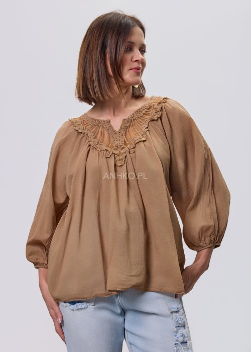 Camelowa bluzka damska z haftem przy dekolcie V i luźnym krojem, zestawiona z jasnymi jeansami w stylizacji casual.