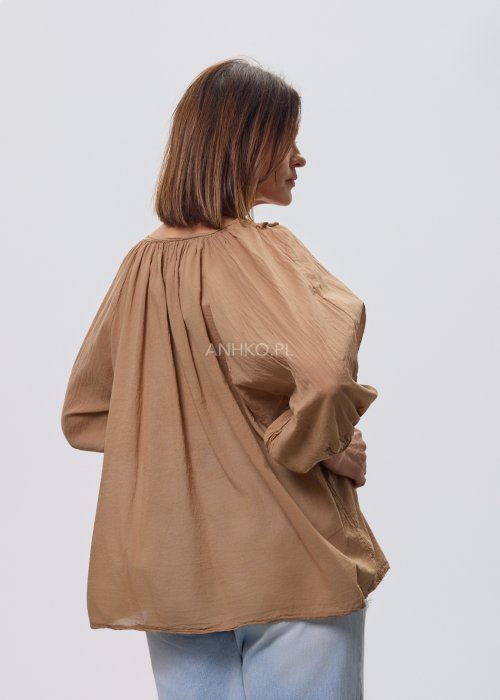 Camelowa bluzka damska z haftem przy dekolcie V i luźnym krojem, zestawiona z jasnymi jeansami w stylizacji casual.