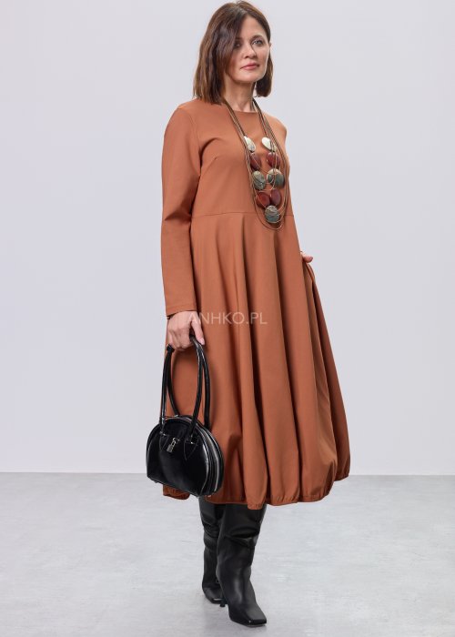 Karmelowa sukienka midi z długim rękawem, odcięciem w talii i kieszeniami, stylizowana z czarnymi kozakami.