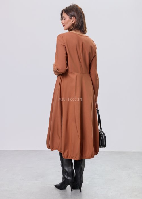 Karmelowa sukienka midi z długim rękawem, odcięciem w talii i kieszeniami, stylizowana z czarnymi kozakami.