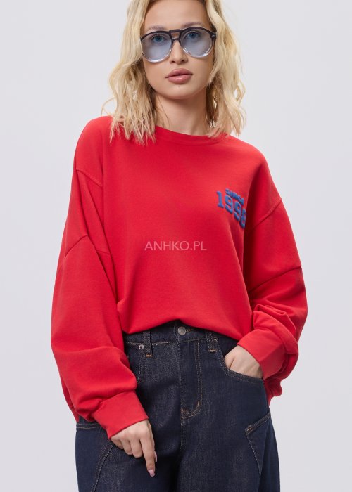 Czerwona bluza damska oversize z nadrukiem Since 1998 z przodu i okrągłą grafiką na plecach, stylizacja z szerokimi jeansami.