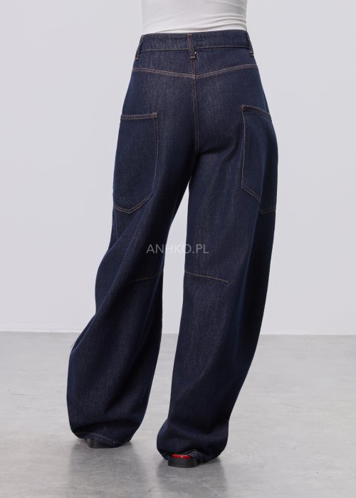 Granatowe jeansy damskie z szeroką nogawką i utility kieszeniami, ozdobne przeszycia, stylizacja z czerwonymi balerinami.