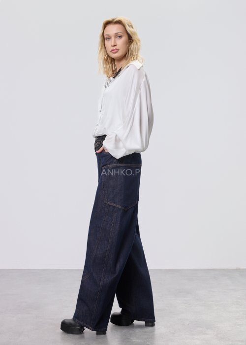 Granatowe jeansy damskie z szeroką nogawką i utility kieszeniami, ozdobne przeszycia, stylizacja z czerwonymi balerinami.