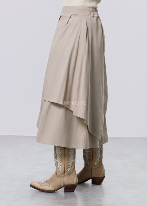Beżowa spódnica midi o asymetrycznym, warstwowym kroju z elastycznym pasem i kieszeniami, stylizowana z kowbojkami.