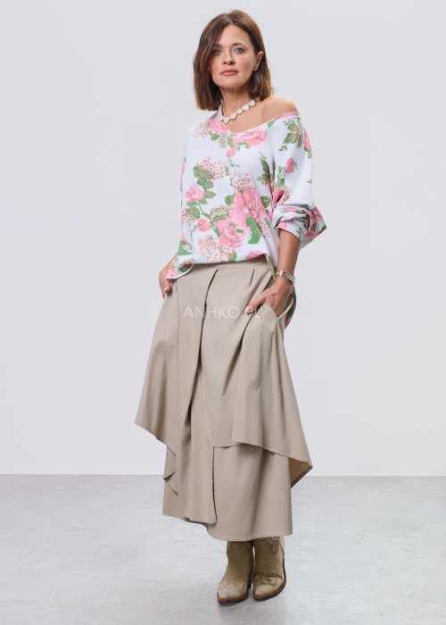 Beżowa spódnica midi o asymetrycznym, warstwowym kroju z elastycznym pasem i kieszeniami, stylizowana z kowbojkami.