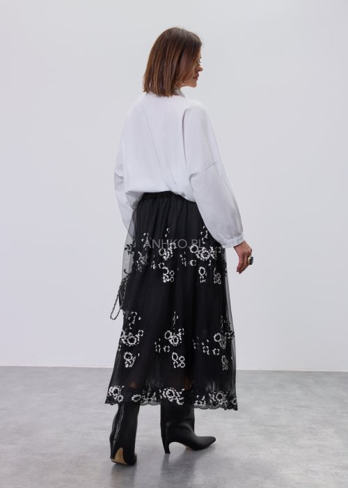 Biała koszula damska z przestrzenną aplikacją 3D na przodzie, luźny fason z długim rękawem, stylizacja z czarną spódnicą tiulową.