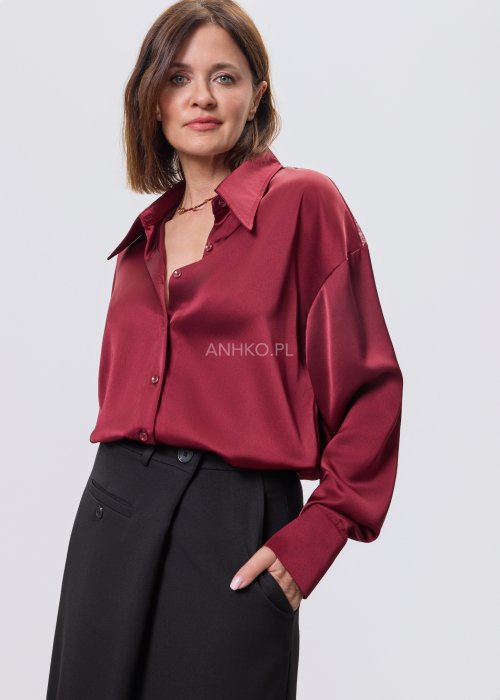 Bordowa koszula damska z satynowym wykończeniem i koronkowym tyłem, zestawiona z czarną spódnicą o rozkloszowanym kroju.