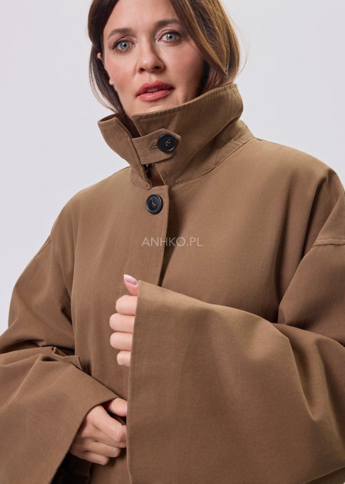 Krótki płaszcz damski w kolorze camel z paskiem i szerokim kołnierzem, stylizowany z czarnym kompletem dzianinowym i botkami.