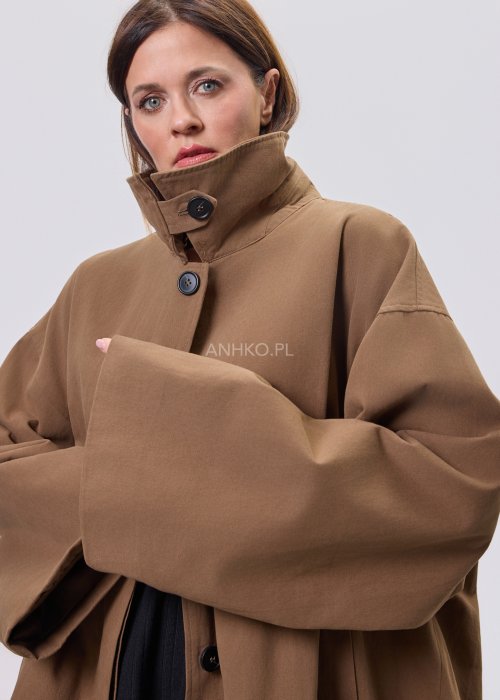 Krótki płaszcz damski w kolorze camel z paskiem i szerokim kołnierzem, stylizowany z czarnym kompletem dzianinowym i botkami.