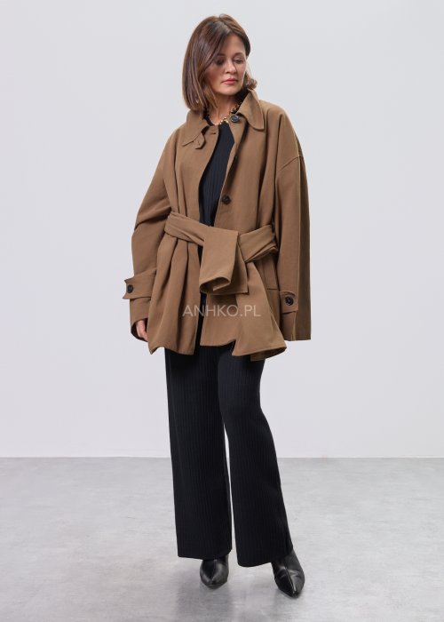 Krótki płaszcz damski w kolorze camel z paskiem i szerokim kołnierzem, stylizowany z czarnym kompletem dzianinowym i botkami.
