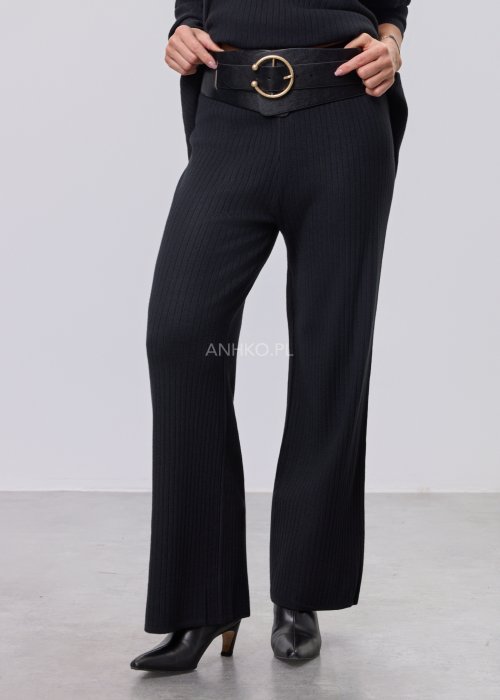 Czarny komplet dzianinowy z bluzką z dekoltem w serek i prostymi spodniami, stylizowany z czarnymi botkami.