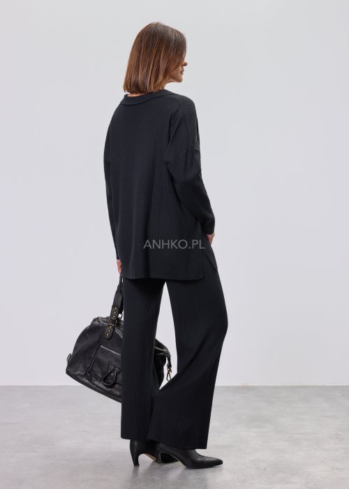 Czarny komplet dzianinowy z bluzką z dekoltem w serek i prostymi spodniami, stylizowany z czarnymi botkami.